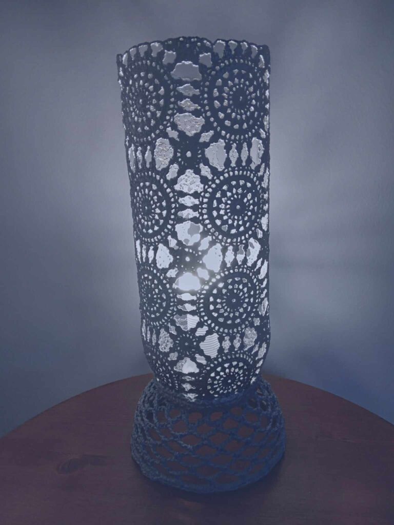 Lampa decorativa de masa cu design rustic oriental. Cod produs: LC-01 Producator: J.S. ArtDesign. Materiale: dantela rigidizata cu rasini speciale pentru materiale textile. Putere: 1x30 Watt, E14, bec exclus din pret. Tensiune: 220-240V, 50-60 Hz. Culoare: gri cu finisaj argintiu antic. Dimensiuni: diametru: 14 cm, inaltime: 31 cm.